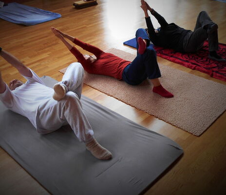 Drei Personen liegen auf Matten und machen eine Feldenkrais-Übung.